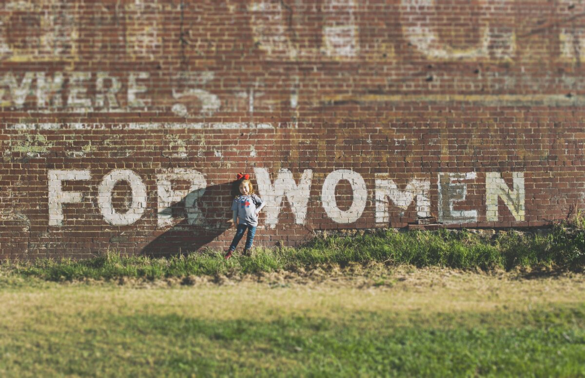 young girl standing in front of wall saying for women