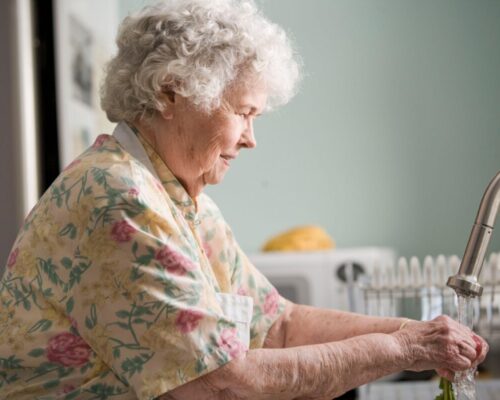 elderly woman at kitchen sink